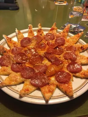 a white plate with a pile of pepperoni pizza at Gasthof Toni in Castelrotto