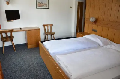 a bedroom with a bed and a desk with a computer at Gasthof Toni in Castelrotto
