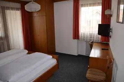 a bedroom with a bed and a desk and a television at Gasthof Toni in Castelrotto