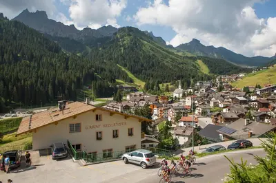 a group of people riding bikes in a town with mountains at Garni Bellavista in Arabba