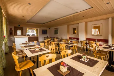 an empty restaurant with wooden tables and chairs at Garni Bellavista in Arabba