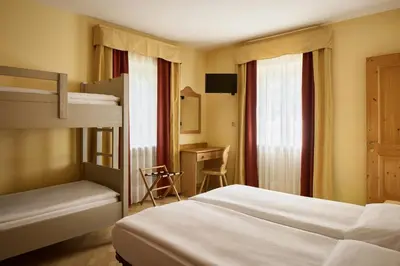 a bedroom with two bunk beds and a desk at Garni Bellavista in Arabba