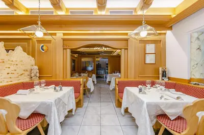 a restaurant with white tables and red chairs at Hotel Ramon in Campitello di Fassa