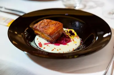 a black plate with a piece of cake and whipped cream at Hotel Ramon in Campitello di Fassa