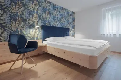 a bedroom with a bed and a chair and a wall at Apartments Haus Gabi in Laion