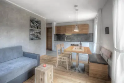 a kitchen and living room with a table and a couch at Apartments Haus Gabi in Laion