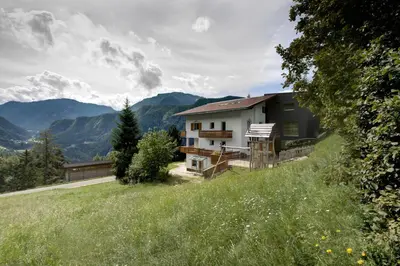 a house on a hill with mountains in the background at Apartments Haus Gabi in Laion