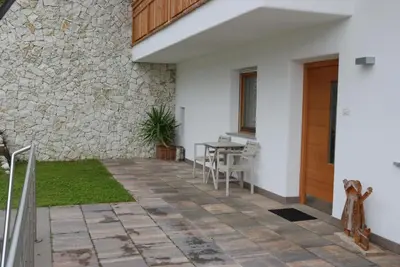 a patio with a table and a stone wall at Ciasa de Zeno in La Valle