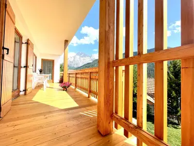a wooden porch with a view of mountains at Ciasa de Zeno in La Valle