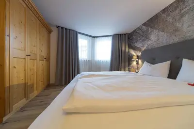 a bedroom with a large white bed and a window at Eden Apartments in Siusi