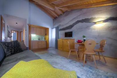 a bedroom with a bed and a table with chairs at Eden Apartments in Siusi