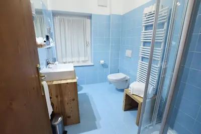 a blue bathroom with a sink and a toilet at Hotel Des Alpes in Cortina dʼAmpezzo