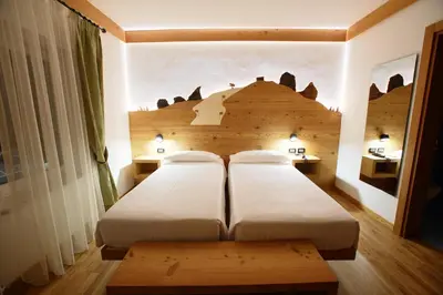 a bedroom with two beds and a wooden headboard at Hotel Des Alpes in Cortina dʼAmpezzo