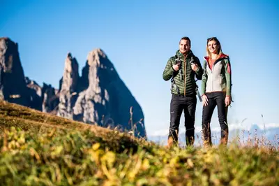 a man and woman standing on a hill with mountains in the background at Lamondis in Castelrotto