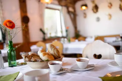 a table with a bowl of bread and cups of coffee at Hotel Restaurant Waldbichl in Verano