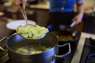 a person cooking food in a pot on a stove at Hotel Restaurant Waldbichl in Verano