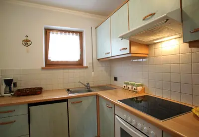 a kitchen with white cabinets and a sink and a window at Ciasa Rudiferia Appartamenti in Alta Badia in Badia