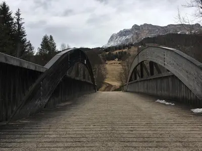 a bridge over a road with a mountain in the background at Ciasa Rudiferia Appartamenti in Alta Badia in Badia
