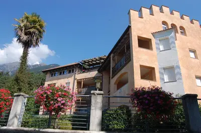 a building with a palm tree in front of it at Appartementhaus Am Waalweg in Rifiano