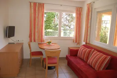 a living room with a red couch and a table at Appartementhaus Am Waalweg in Rifiano