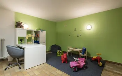 a childs room with green walls and toys on the floor at Pension Prack in Brunico