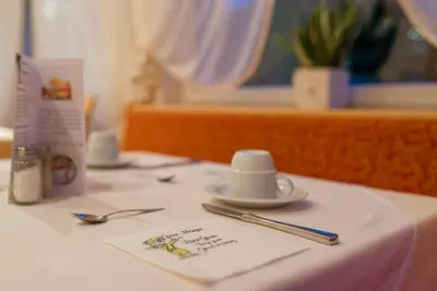 a table with a white table cloth with a plate and spoon at Pension Prack in Brunico