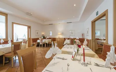 a dining room with tables and chairs in a restaurant at Pension Prack in Brunico