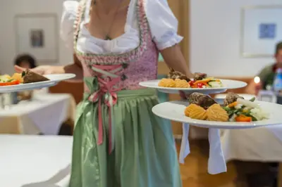 a woman is holding two plates of food at Pension Prack in Brunico