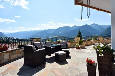 a patio with chairs and tables and a view of mountains at BB le Fontanelle in Carano