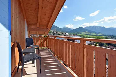 two chairs on a balcony with mountains in the background at BB le Fontanelle in Carano