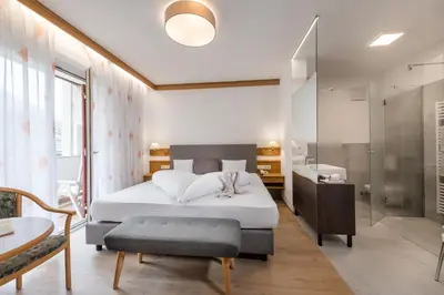 a bedroom with a white bed and a bathroom at Hotel Wilma in Nalles