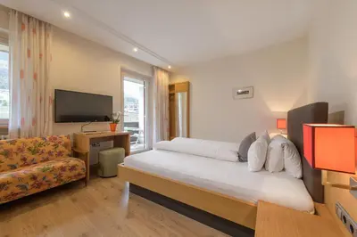 a bedroom with a bed and a couch and a television at Hotel Wilma in Nalles