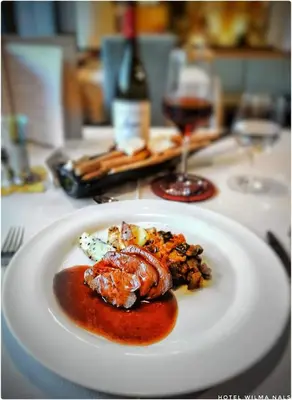 a plate of food on a table with a glass of wine at Hotel Wilma in Nalles