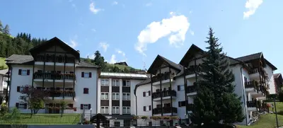 a large white building with a tree in front of it at Apartments Casa Metz in Santa Cristina in Val Gardena