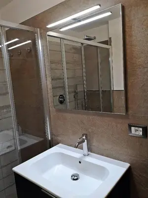 a bathroom with a sink and a mirror and a shower at Apartments Casa Metz in Santa Cristina in Val Gardena