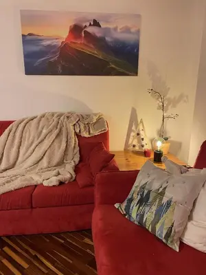 a living room with a red couch with a blanket at Apartments Casa Metz in Santa Cristina in Val Gardena