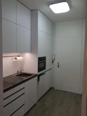 a kitchen with white cabinets and a sink and a door at Nadia's Home in Merano