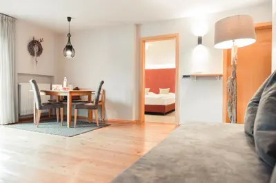 a room with a table and chairs and a bedroom at Hotel Tiefenbrunn Gardensuites & Breakfast in Lana