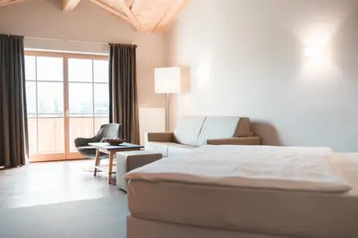 a bedroom with a bed and a living room with a couch at Hotel Tiefenbrunn Gardensuites & Breakfast in Lana
