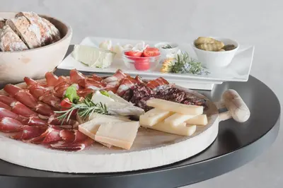 a plate of cheese and other foods on a table at Hotel Tiefenbrunn Gardensuites & Breakfast in Lana