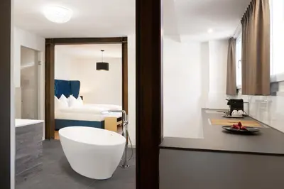a bathroom with a bath tub and a bedroom at Parkhotel Post in Chiusa