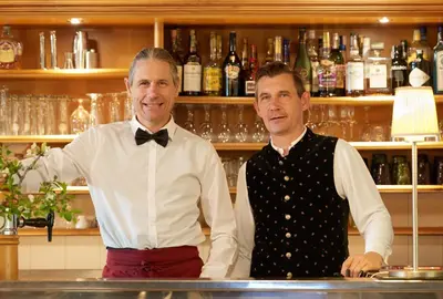 two men standing behind a counter in a bar at Parkhotel Post in Chiusa