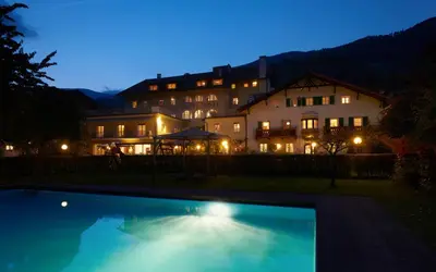 a large house with a swimming pool at night at Parkhotel Post in Chiusa
