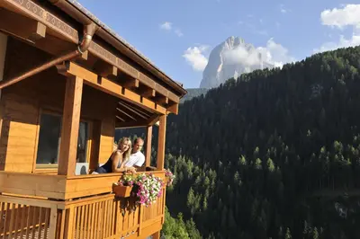 two people sitting on a balcony of a cabin at Residence Sovara in Santa Cristina in Val Gardena