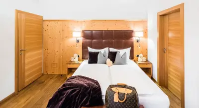 a bedroom with a large bed with a suitcase on it at Residence Sovara in Santa Cristina in Val Gardena