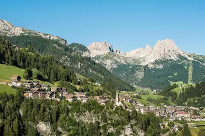 a town on a hill with mountains in the background at Residence Sovara in Santa Cristina in Val Gardena