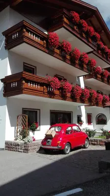 a red car parked in front of a building at Hotel Garni Walter in Ortisei
