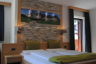 a bedroom with two beds and a brick wall at Hotel Garni Walter in Ortisei