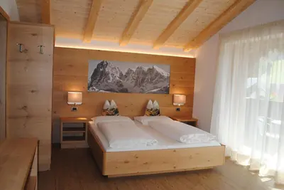 a bedroom with a large bed in a wooden wall at Hotel Garni Walter in Ortisei