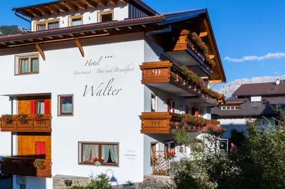 a white building with flower boxes and balconies at Hotel Garni Walter in Ortisei